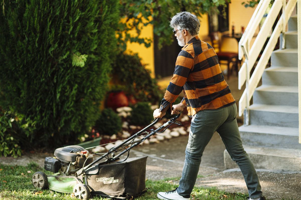 A crew member mowing a suburban lawn in clean stripes