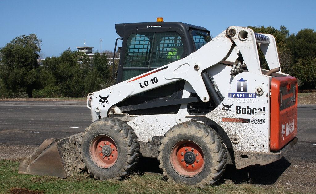 A skid-steer loader moving soil on a job site