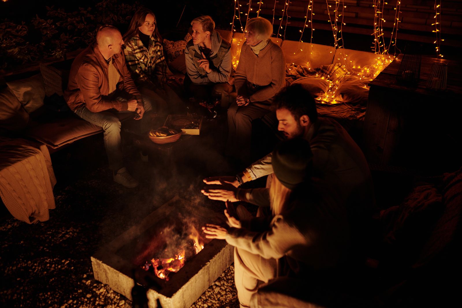 Friends gathered around a backyard bonfire at night