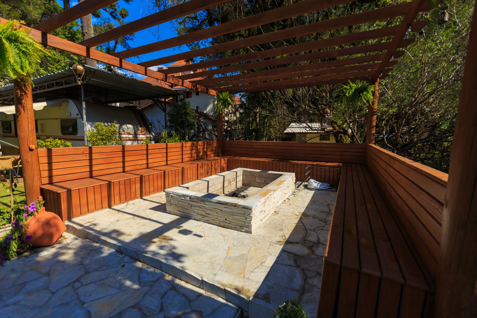 Stone fire pit beneath a wooden pergola