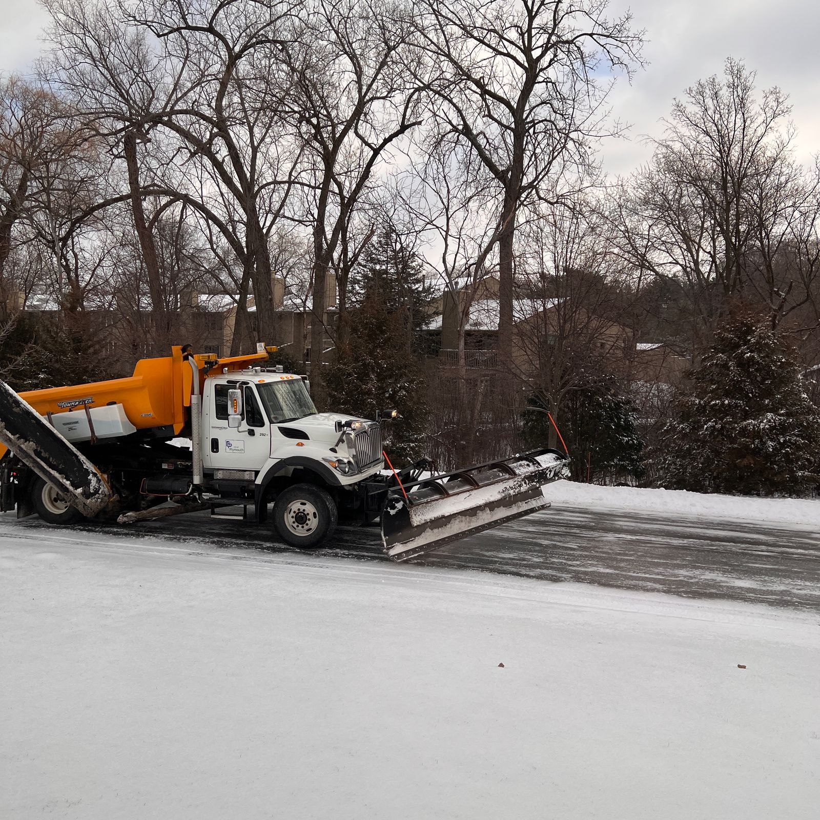 Heavy plow truck clearing an icy residential road