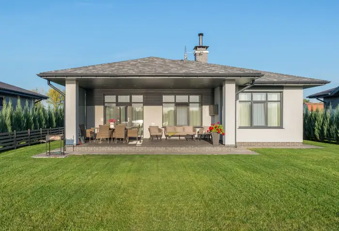 Wide mown lawn behind a single-storey house with a covered patio