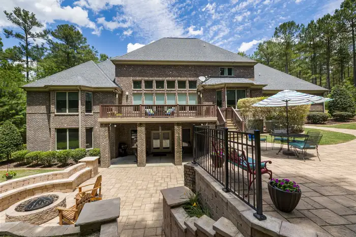 Paver patio with a sunken fire pit and seating behind a large brick house
